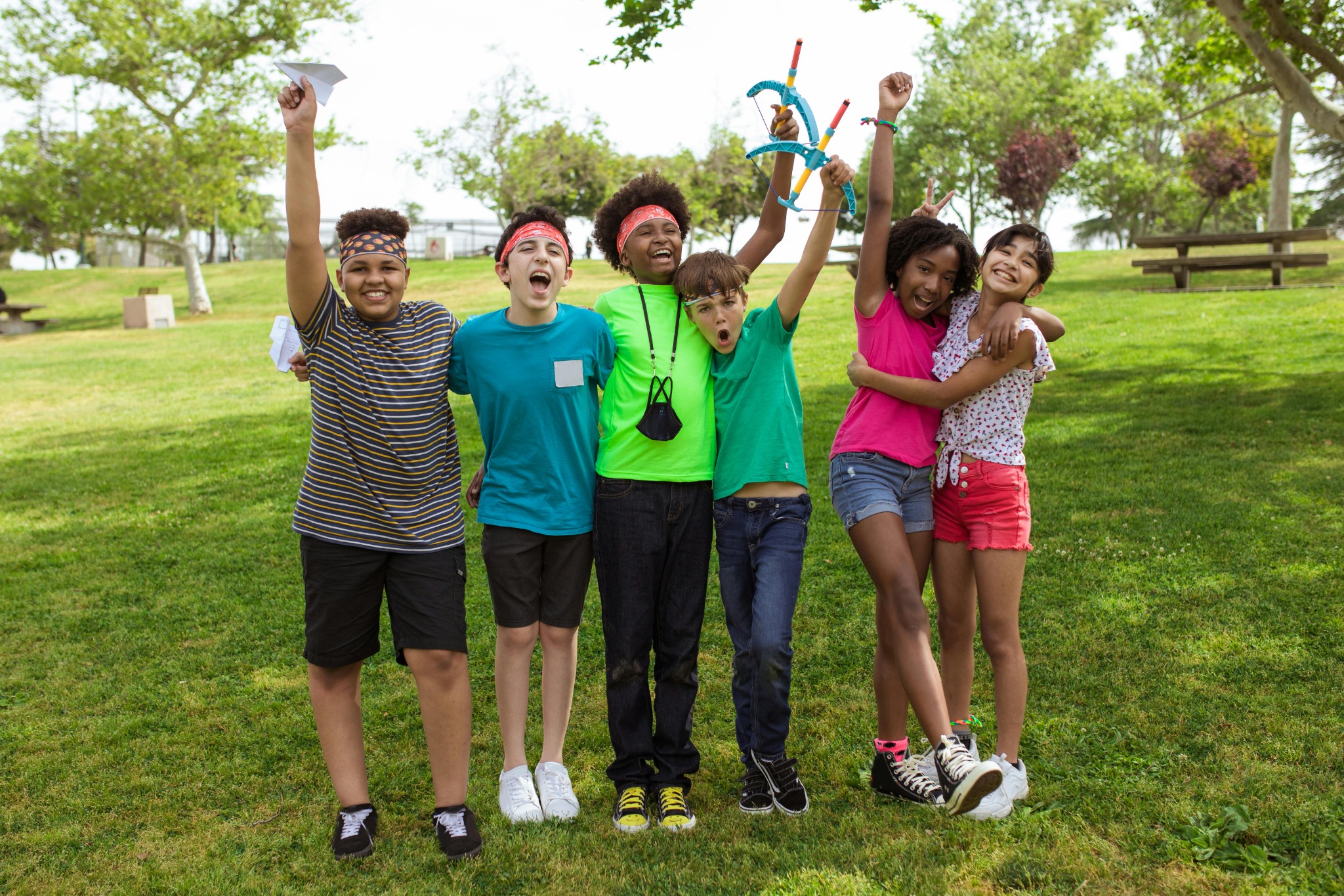 Group of diverse kids smiling and celebrating together at the park.